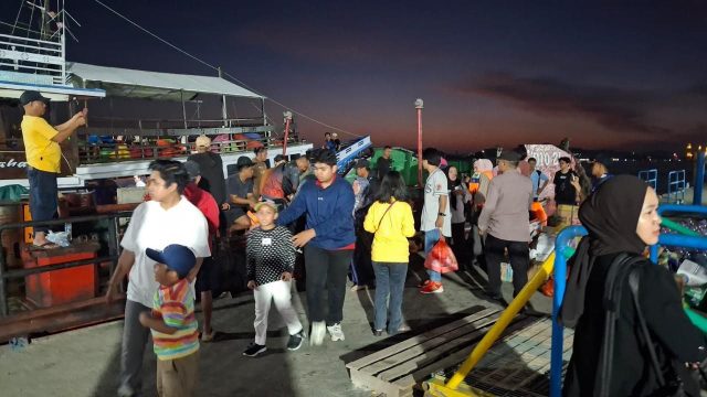 Petugas Polsek Kawasan Pelabuhan Samarinda membantu proses evakuasi penumpang KM Teman Bejalanan saat insiden kebakaran di Dermaga Pasar Pagi.